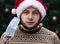 Wearing a mask incorrectly. Close up Portrait of man wearing a santa claus hat, xmas sweater and medical mask with emotion.