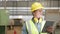 Wearing a safety uniform and a hard hat, a professional heavy industry engineer/worker uses a tablet computer. An African American