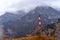 Weather vane on a background of mountains with fog and clouds above them