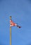 A weatherbeaten tattered UK Union Flag against a bright blue sky