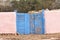 Weathered blue gates with pink adobe walls