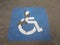 Weathered blue wheelchair symbol on black asphalt