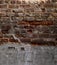 Weathered and decaying brick wall with multiple layers of concrete and tuckpointing