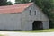 Weathered grey Amish barn with red metal roof