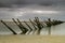 Weathered groynes in sea under dark clouds