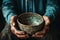 Weathered hands, empty bowl on wood backdrop, evoke the harshness of hunger