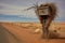 a weathered mailbox with a tumbleweed nearby in a barren desert