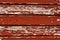 Weathered old horizontal wooden plank wall with peeling red paint texture