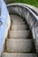 Weathered outdoor concrete stairs curving down into an unknown destination, blue wall and metal handrail