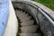 Weathered outdoor concrete stairs curving down into an unknown destination, blue wall and metal handrail