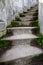 Weathered outdoor concrete stairs curving up into an unknown destination, moss growing on the stairs in a wet environment