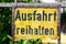A weathered, rusty, yellow sign with the words `Einfahrt freihalten`, translation: keep gateway clear, in black letters.
