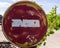 Weathered, scratched and dirty old red and white round No entry road sign with muddy road leading