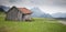 Weathered slate hay meadow  with a bench and a path that leads through the photo. In the background high jagged mountains in the a