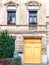 Weathered vintage building facade with flower pots decorated windows and vibrant yellow door