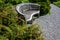 Weathered wooden bench beside a gravel path in a sunny garden