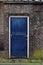 Weathered wooden blue door in brick wall