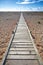 Weathered wooden boardwalk, disappears towards a lovely blue sky.