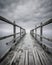 Weathered wooden pier with railing flowing into water