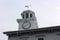 Weathervane on top of large white building with working clock