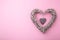 Weaved wooden heart on pink background, top view