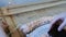 Weaving on a loom. Closeup woman`s hands running on a loom. Threading the needle through the strands of frame and fasten