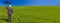 Web banner panoramic business concept photograph of a businessman standing in a green field under a bright blue sky holding and