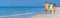 Web banner panoramic happy family of mother, father and two children, son and daughter, walking on a beach