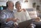 Web surfing with laptop and headphone. Two senior people share the laptop looking and planning a new travel. White hair - couple