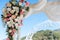 Wedding arch detail - pink and white flowers arranged with an ethereal veil against blue sky