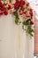 Wedding arch draped with white fabric and decorated with red, pink and white flowers