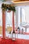 Wedding arch draped with white and pink fabric, white and red flowers on the top, decorative lamps with candles on the sides