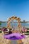 Wedding arch with gold luxury frame and purple flower and chair on riverside. Bride and groom ceremony