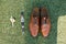 Wedding attributes of the groom: boutonniere, brown shoes and watches on the green grass