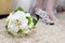 Wedding bouquet: freesias, orchids and roses. Bride`s shoes in the background