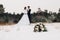 Wedding bouquet lying on snowy ground with couple in background