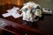 Wedding bouquet of peonies and roses lying on a wooden vintage table near wedding rings on the background of the invitation in the