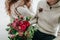 Wedding bouquet with red and crimson flowers on blurred bride and groom background. Winter wedding outdoors