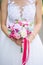 Wedding bouquet of white and pink lowers in the hands of the bride