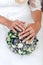 Wedding bouquet of white and purple roses in the hands of brides, close-up, on a white dress background