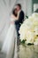 Wedding bouquet of white roses, blurred couple on background, selective focus