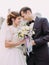 The wedding bouquet of white rosses at the blurred background of the newlyweds.