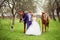 Wedding bride and groom walk with horses in the spring garden
