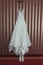 Wedding brides dress and shoes hang on texture wall