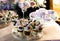 A wedding cake decorated with flowers stands on a festive table with desserts, tartlets and cupcakes