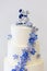 Wedding cake detail with white frosting and small blue flowers and a dutch topper - wedding cake series