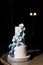 A wedding cake. Sweets. Wedding cake on a black background three floors with white mastic decorated with blue and blue orchids