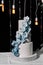 A wedding cake. Sweets. Wedding cake on a black background three floors with white mastic decorated with blue and blue orchids