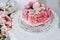 Wedding cake on a white pedestal decorated with fresh flowers