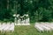 wedding ceremony in a beautiful garden. white chairs and mirrored tables. Glass vase with flowers calla lilies amaryllis